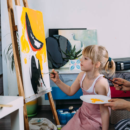 beautiful mother artist and her child paint picture at home with acrylic paints.